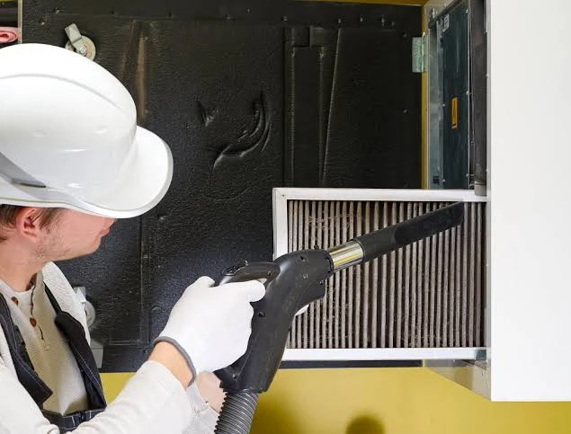 Technician vacuum cleaning an HVAC air filter