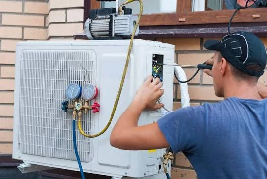 Technician servicing an outdoor heat pump with diagnostic gauges