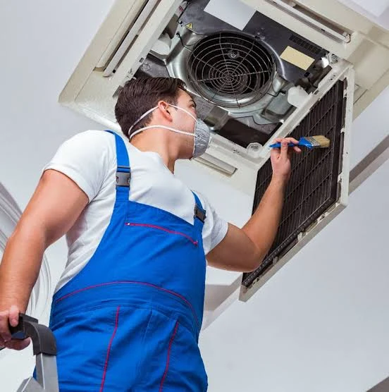Technician cleaning the filter of a ceiling-mounted HVAC unit
